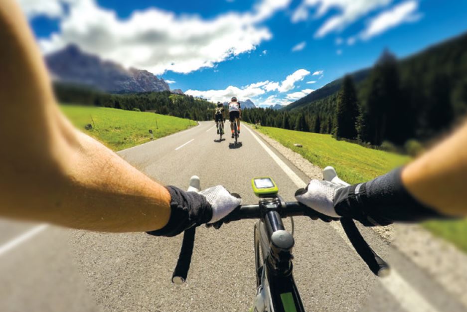View through bike handlebars following two cyclists through mountains