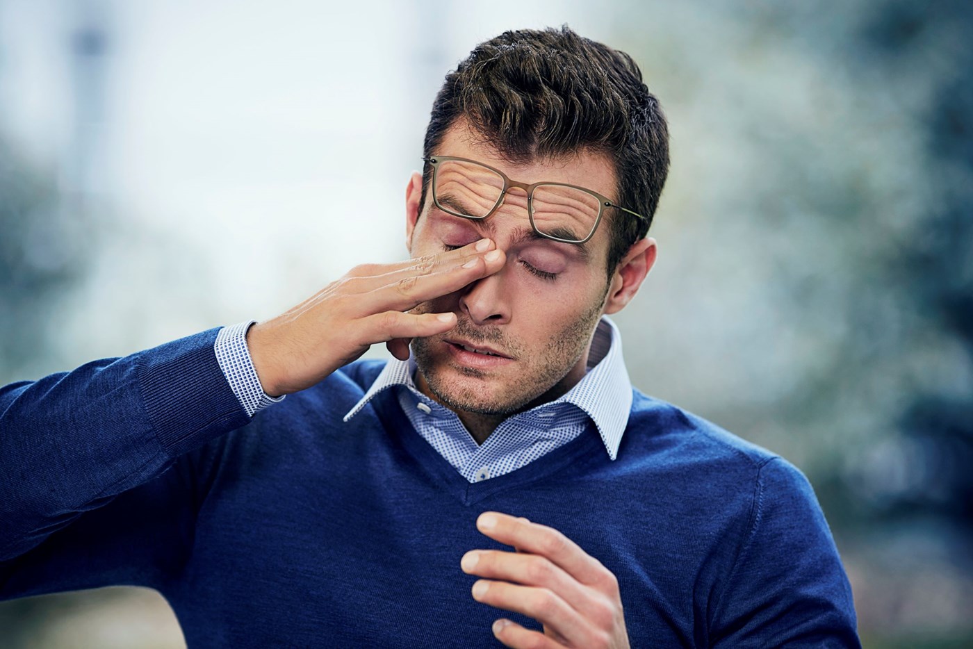 Male rubbing eyes with glasses on top of head