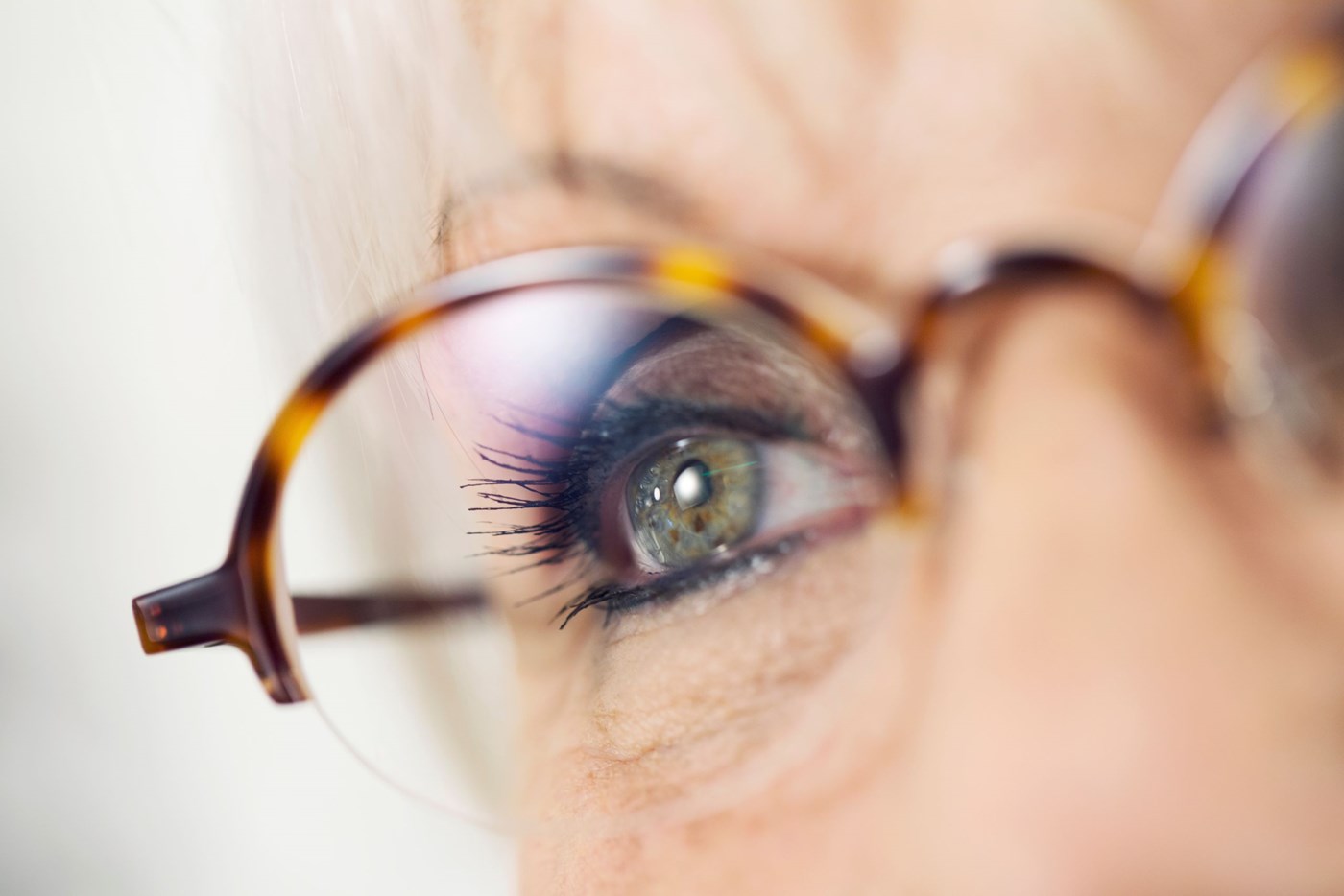 Up close shot of older female eye behind eyeglass lenses