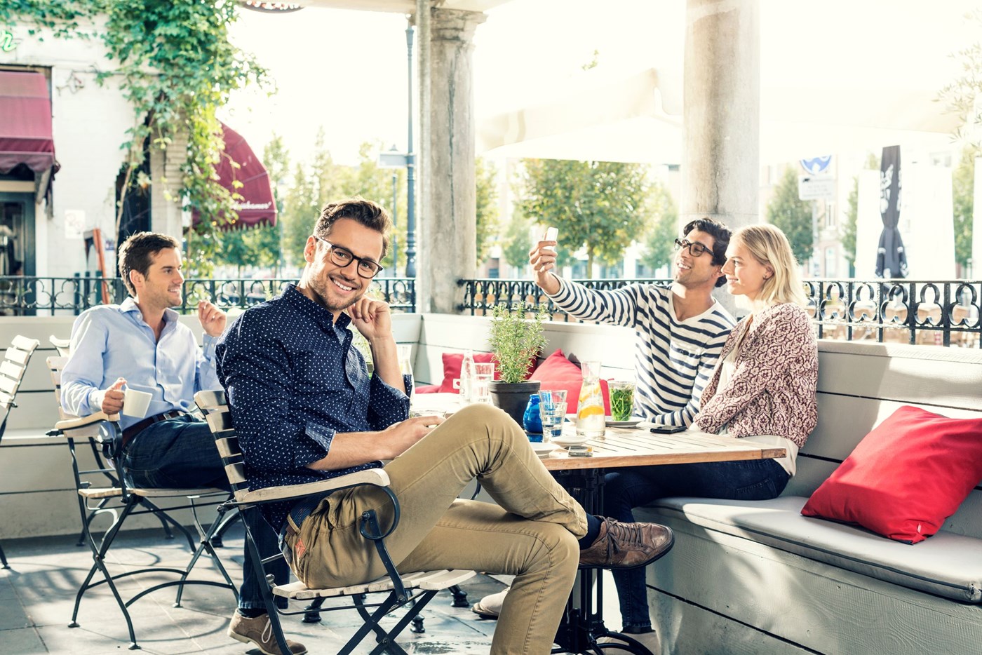 Male sat at table with three others wearing eyeglasses and looking at camera