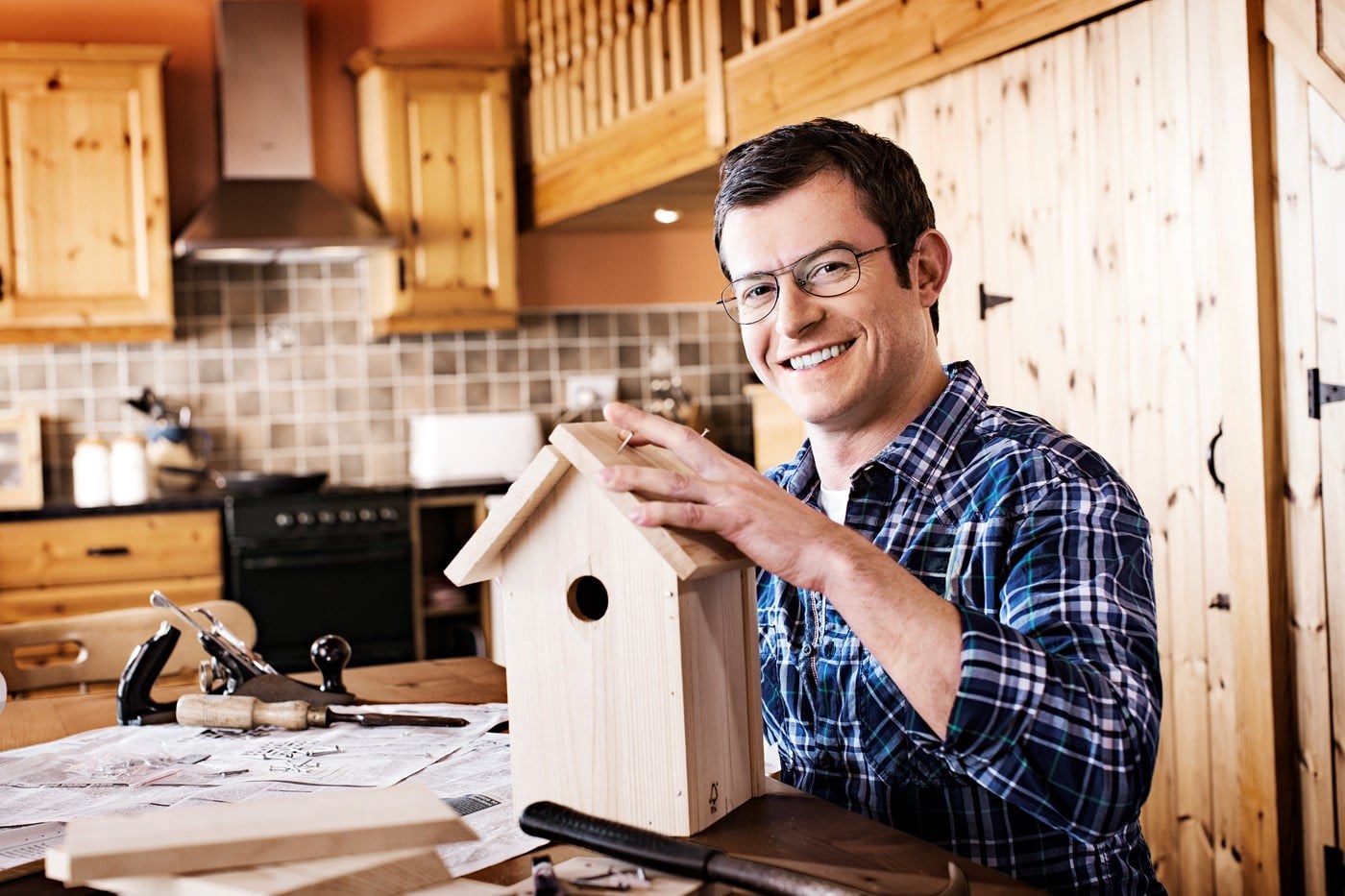 Male wearing eyeglasses building wooden bird house