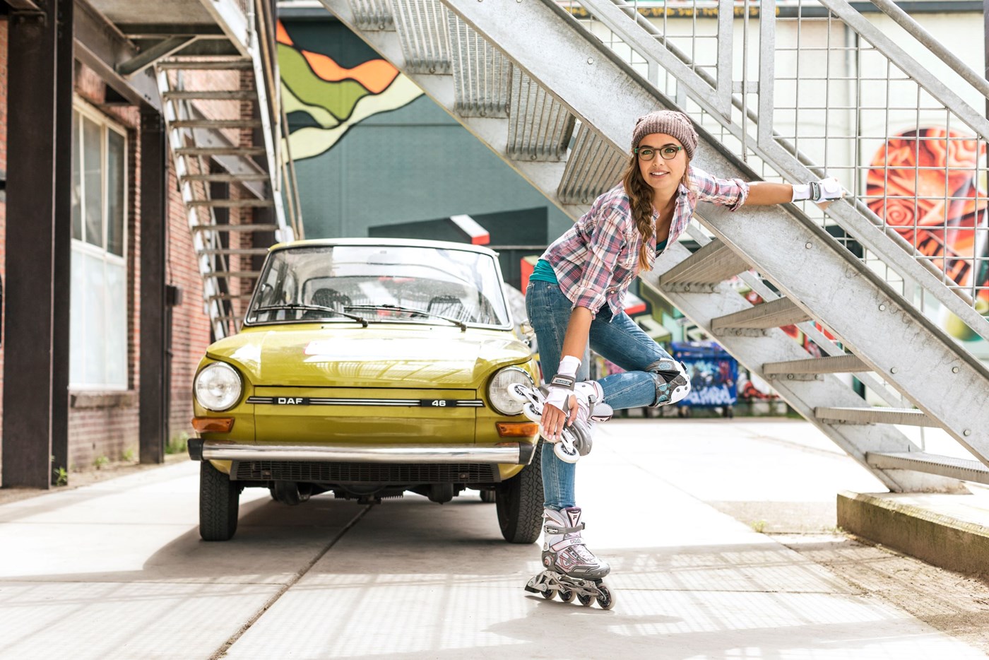 Female roller skater wearing eyeglasses infront of car beside outdoor staircase