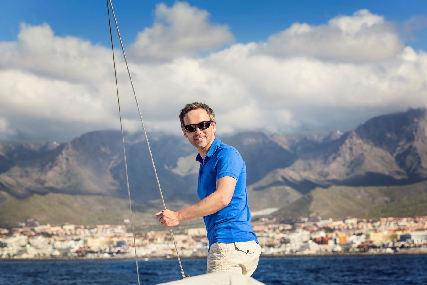 Male on boat wearing polarized sunglasses holding onto rope