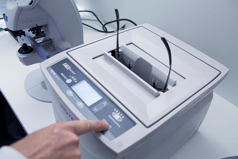 Male optician putting eyeglasses in machinery