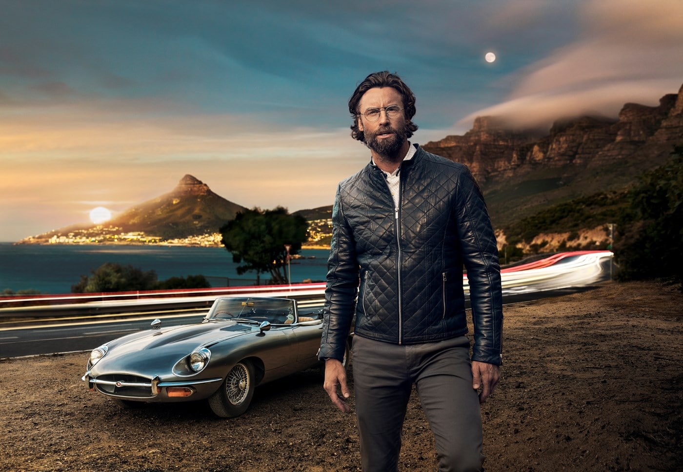 Male wearing eyeglasses in front of vintage car beside tunnel entrance