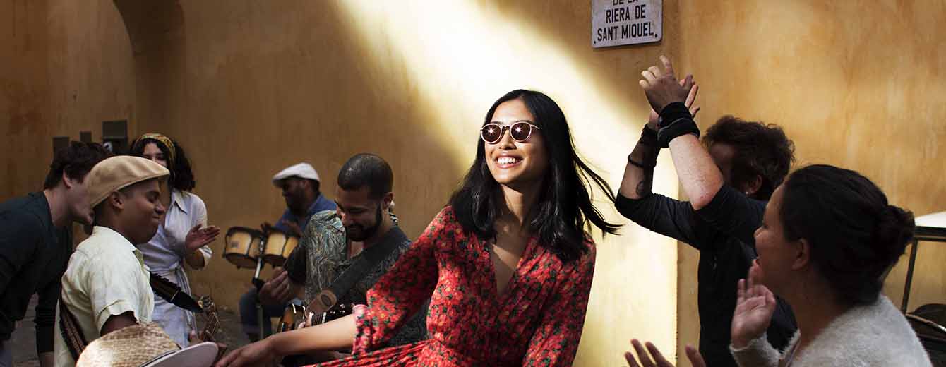 Female wearing sunglasses dancing in street surrounded by people