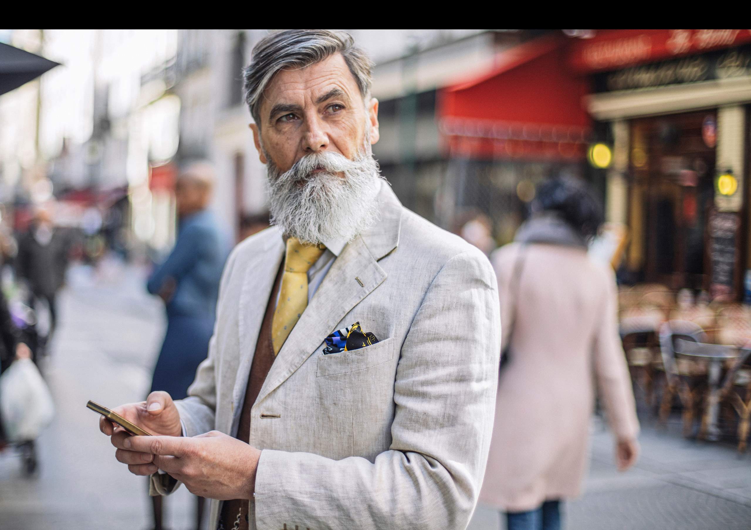 Male with grey beard in suit on a mobile phone